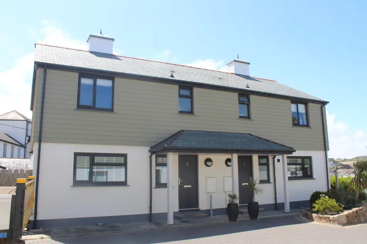 A pair of newly built houses at Copperhouse Mews, Hayle, with cream weatherboard above white render.