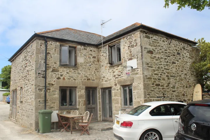 A granite farmhouse at Gwithian Farm Campsite, with white-painted window surrounds and a slate roof.