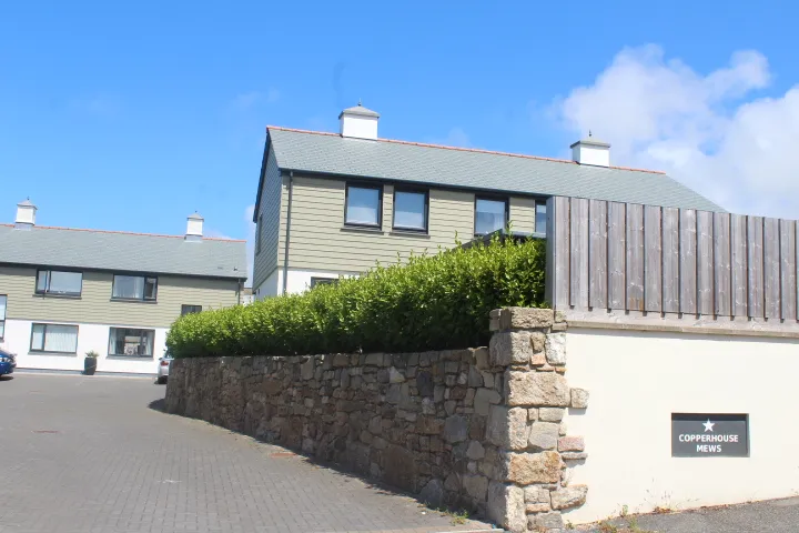 The entrance to Copperhouse Mews in Hayle, with a granite boundary wall and the development sign.