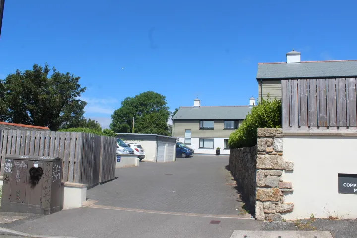 The block-paved parking courtyard at Copperhouse Mews, Hayle, with houses either side.